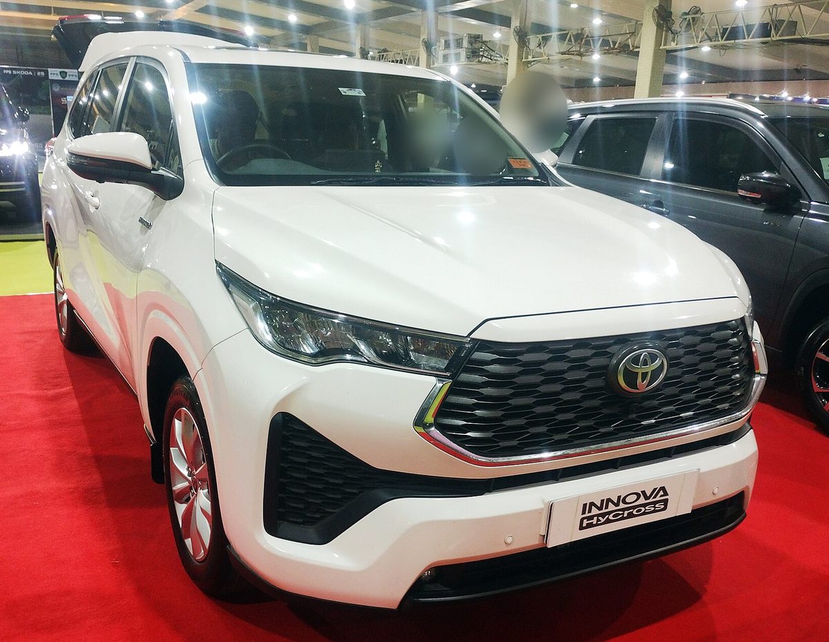 Toyota Innova Hycross in white at an auto show, front three-quarter view