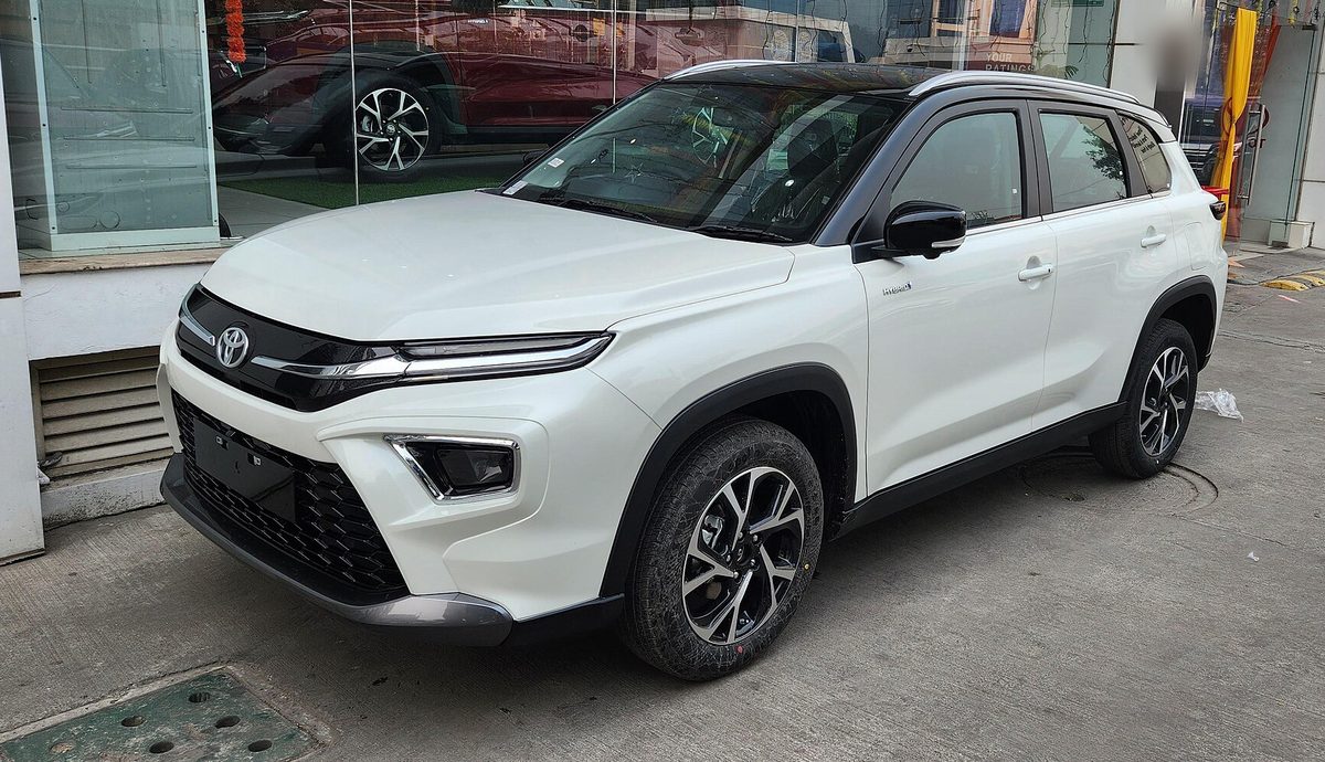 Toyota Urban Cruiser Hyryder strong hybrid in white with a black roof outside a showroom in Goa, front three-quarter view